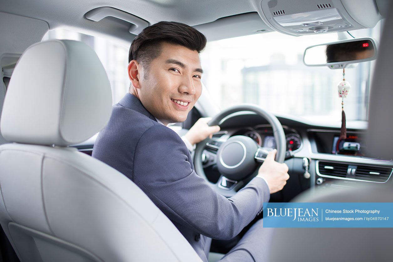 Confident Chinese businessman driving car