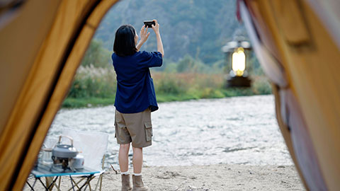 Cheerful young Chinese woman taking photos outdoors