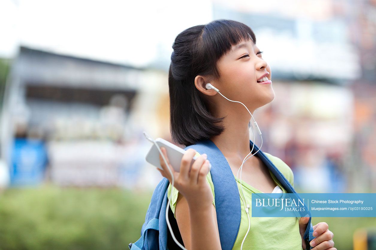 Chinese schoolgirl listening to music on the smart phone