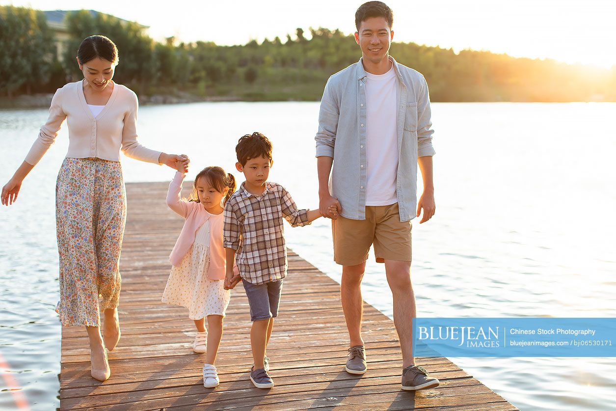 Happy young Chinese family relaxing in park