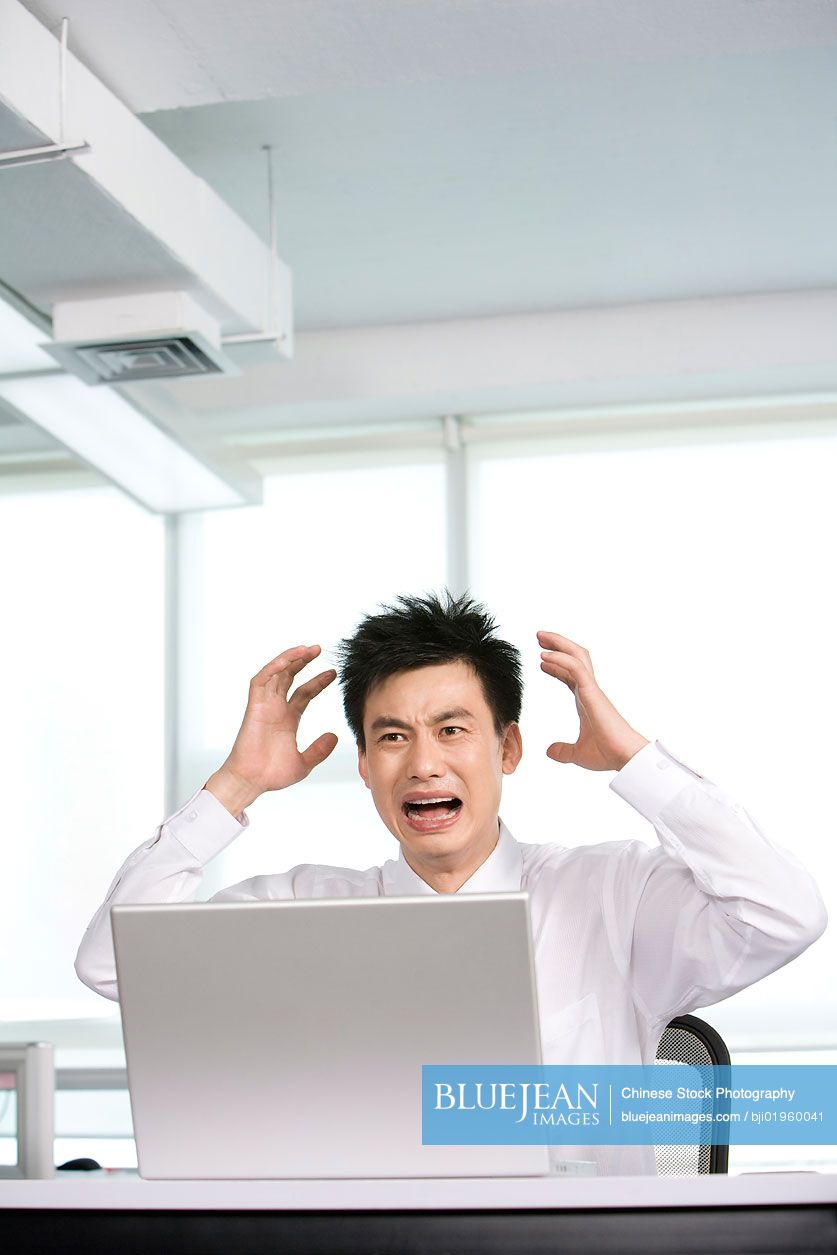 Frustrated Chinese office worker at his desk