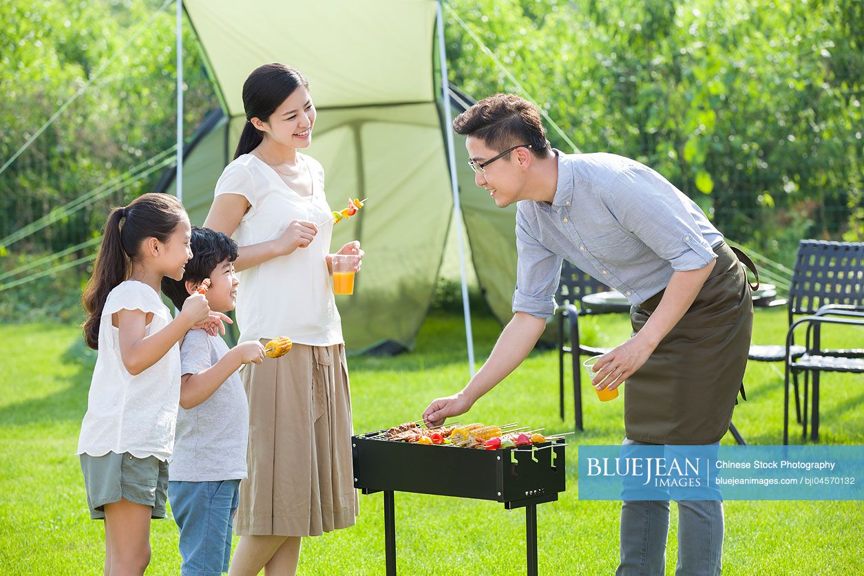Young Chinese family barbecuing outdoors