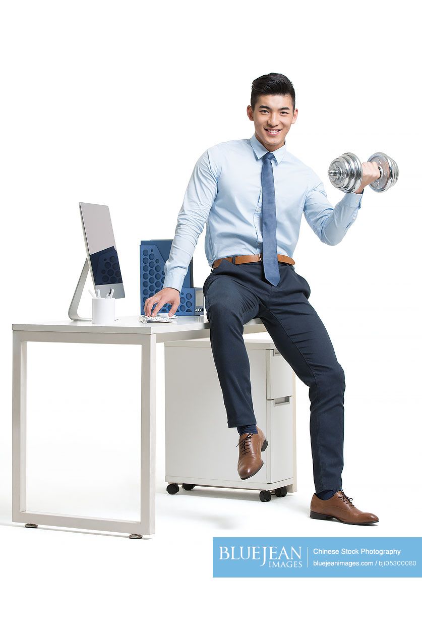 Young Chinese businessman lifting weights in office