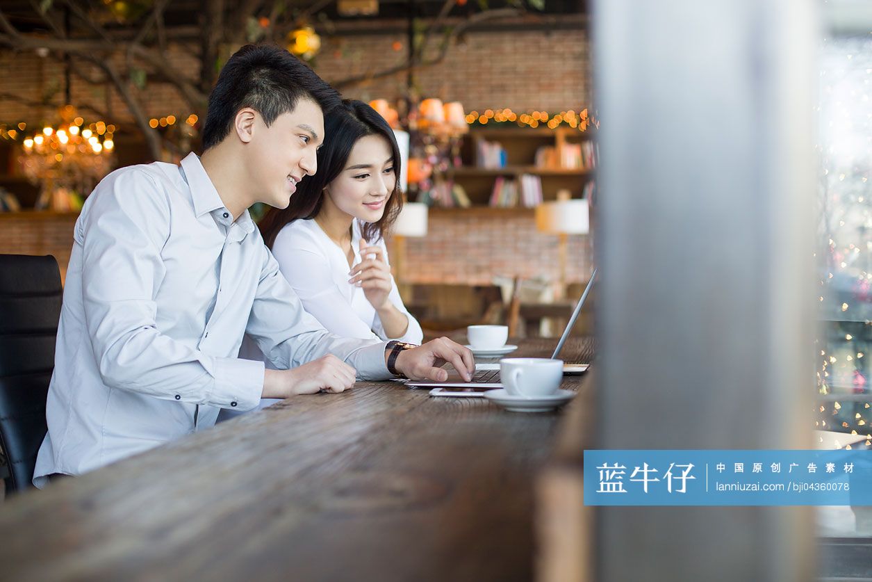 年轻男女在咖啡馆使用笔记本电脑