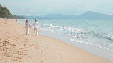快乐老年夫妇在沙滩散步