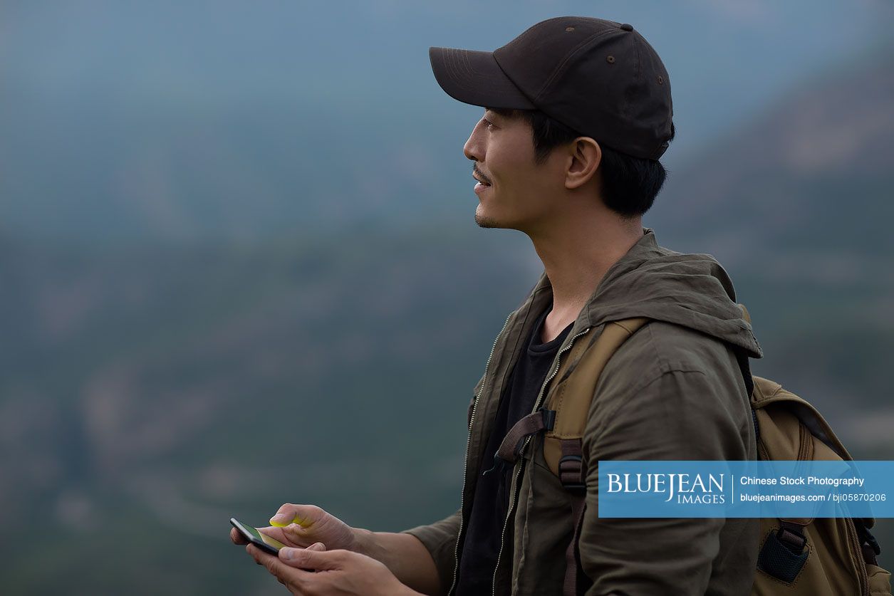 Young Chinese man using smartphone outdoors