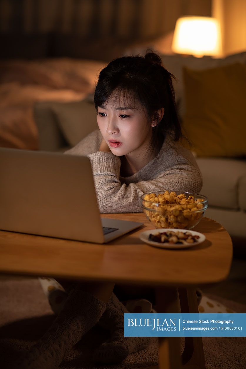 Young Chinese woman watching movie on laptop
