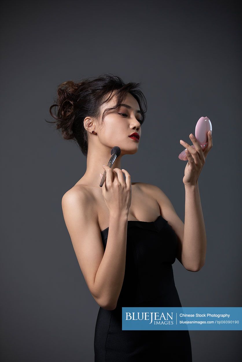 Beautiful young Chinese woman applying makeup