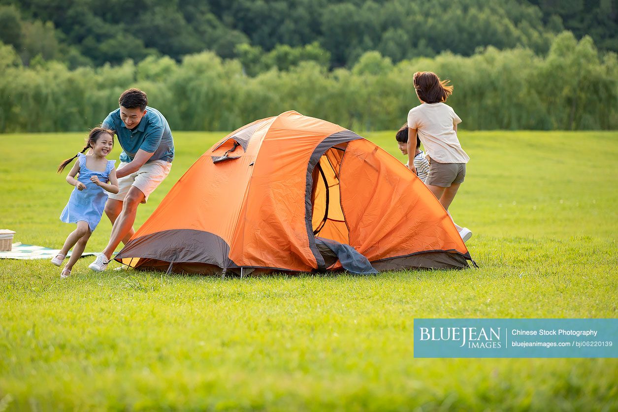 Happy young Chinese family camping outdoors