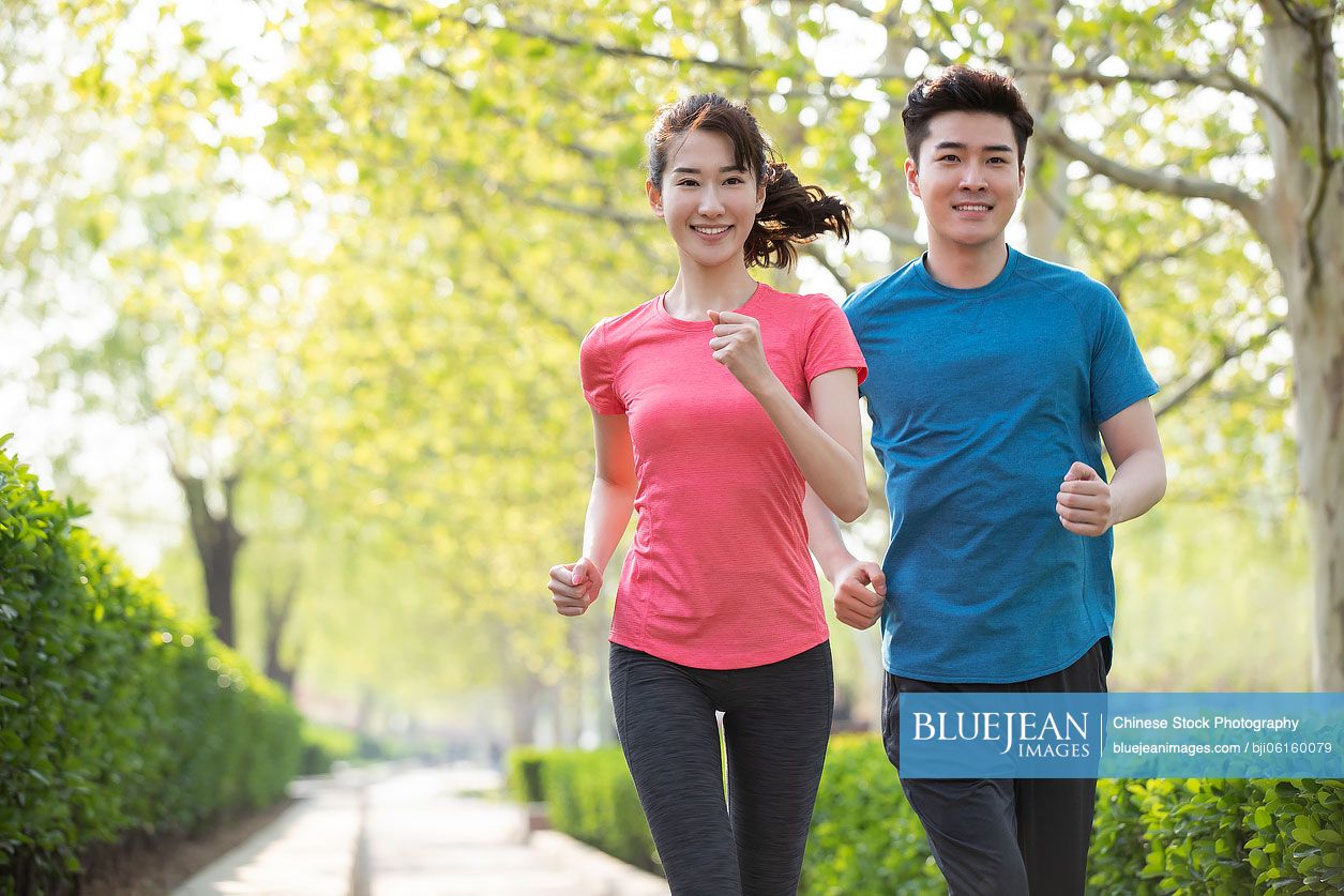 Happy young Chinese couple running in park