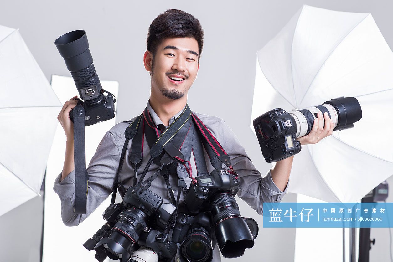 一个摄影师拿着很多单反相机