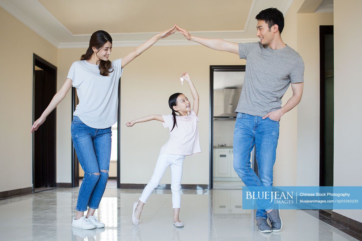 Happy young Chinese family holding keys in their new house