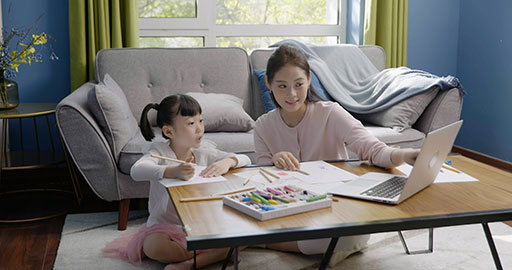 Little girl drawing with her mom by her side