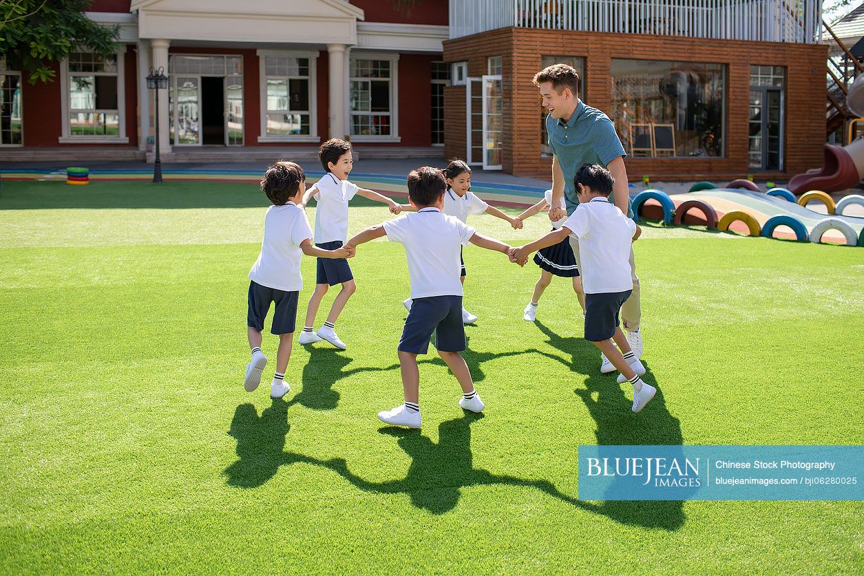 Foreign teacher and children playing in kindergarten playground