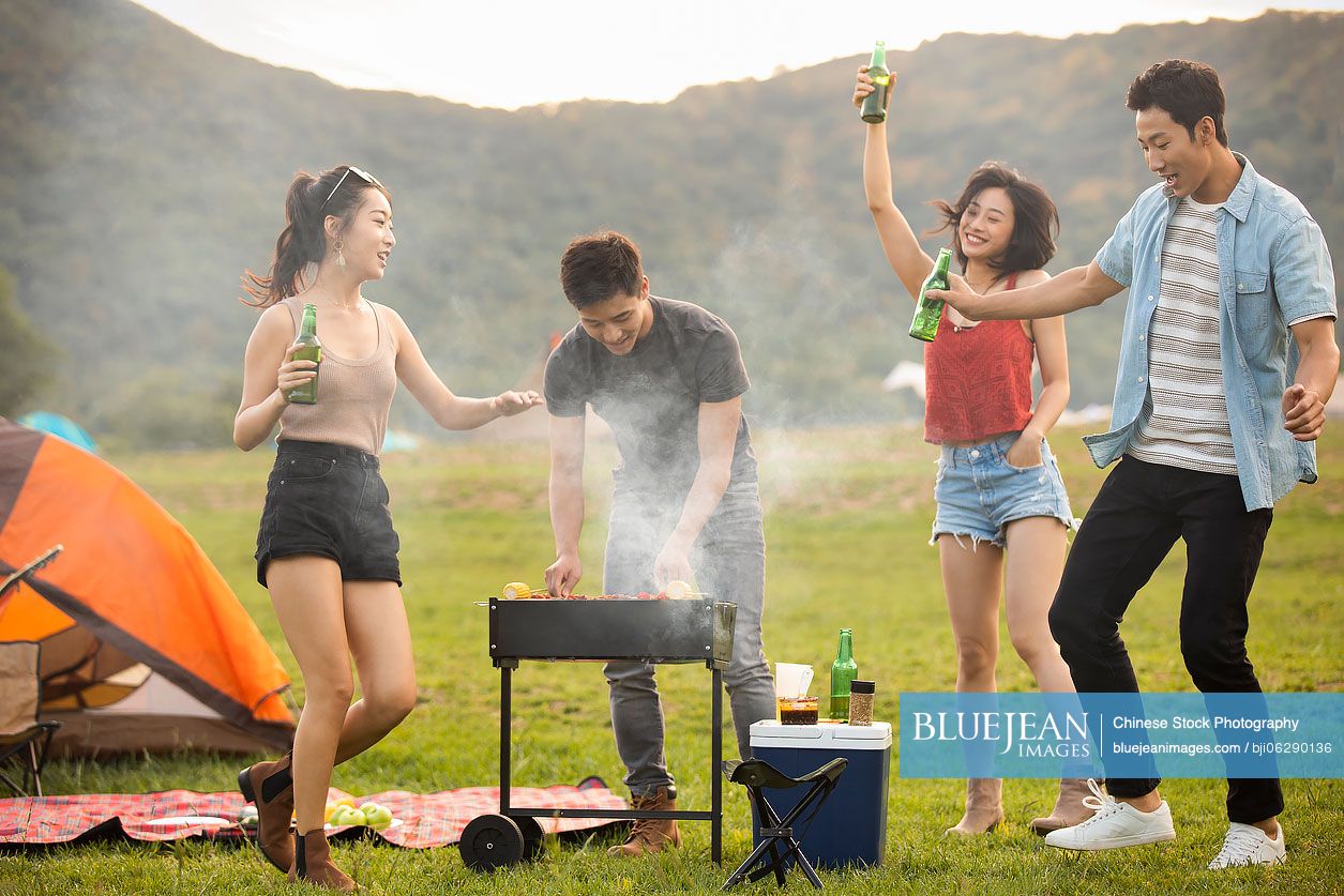 Happy young Chinese friends barbecuing outdoors