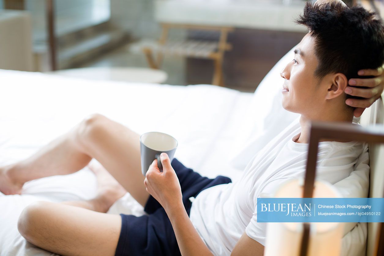 Young Chinese man drinking coffee at home