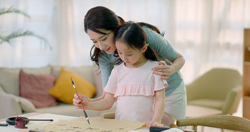 Happy Chinese mother and daughter writing calligraphy at home,4K