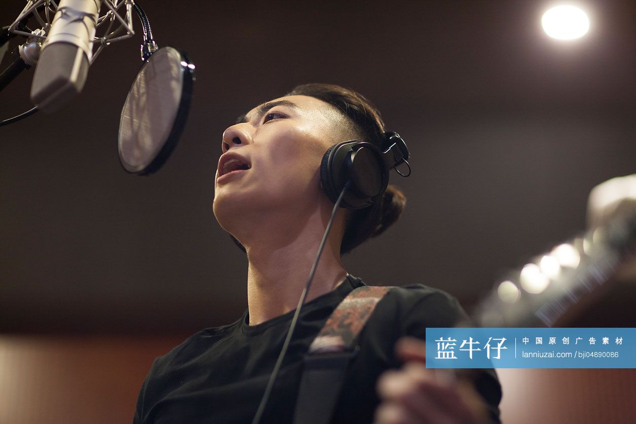 年轻男子在录音棚唱歌弹吉他