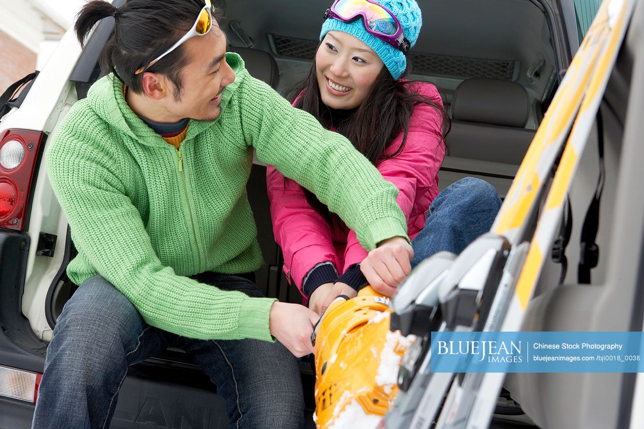 Chinese man helping woman to put on her ski boots