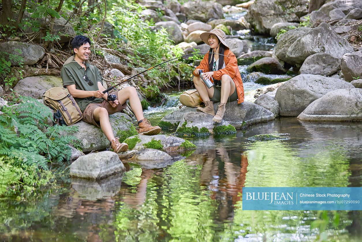Happy couple fishing by the stream, quietly enjoying the serene surroundings