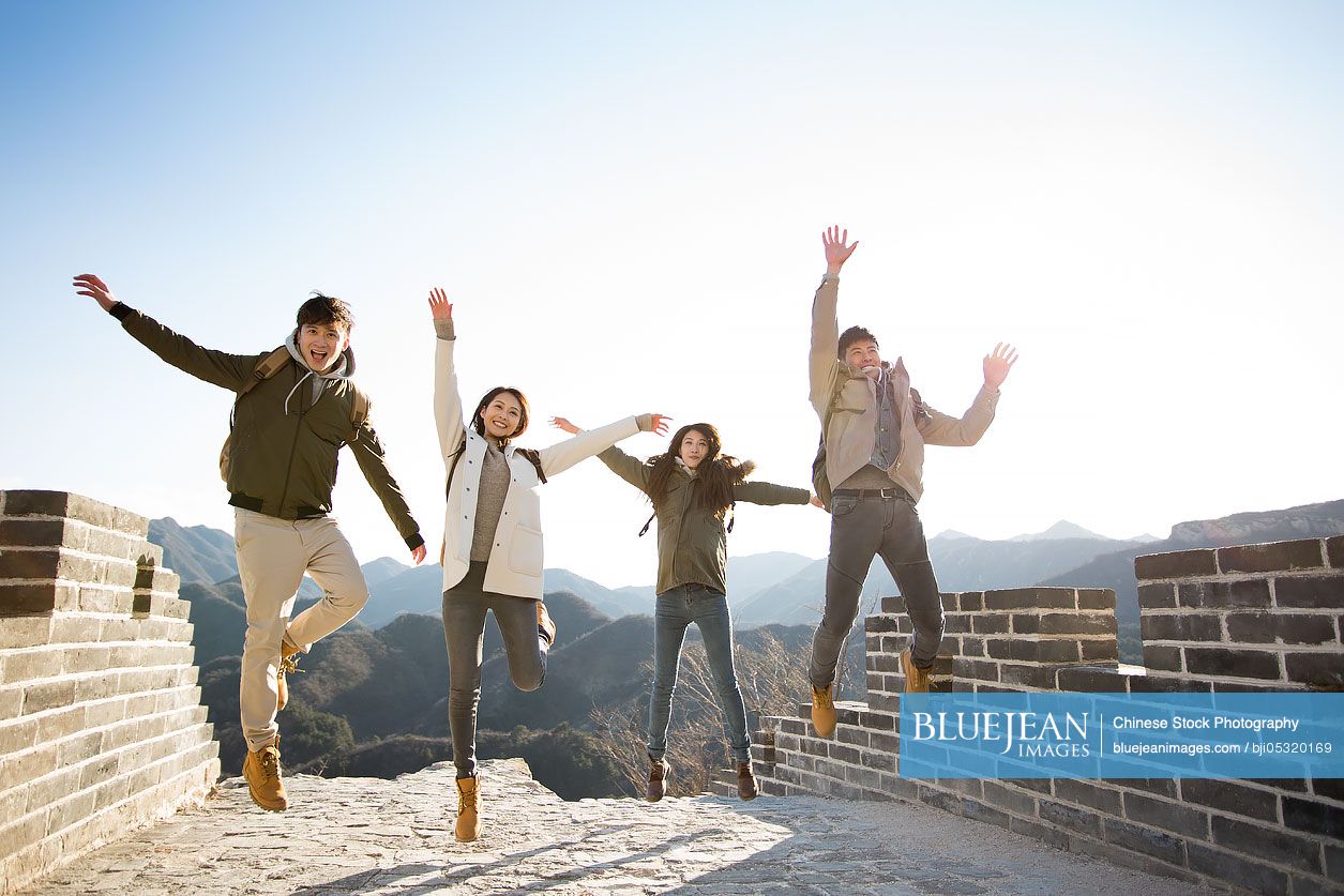 Happy young Chinese friends jumping on the Great Wall