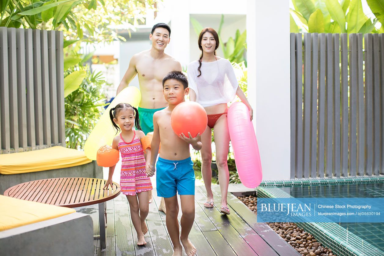 Happy young Chinese family going swimming