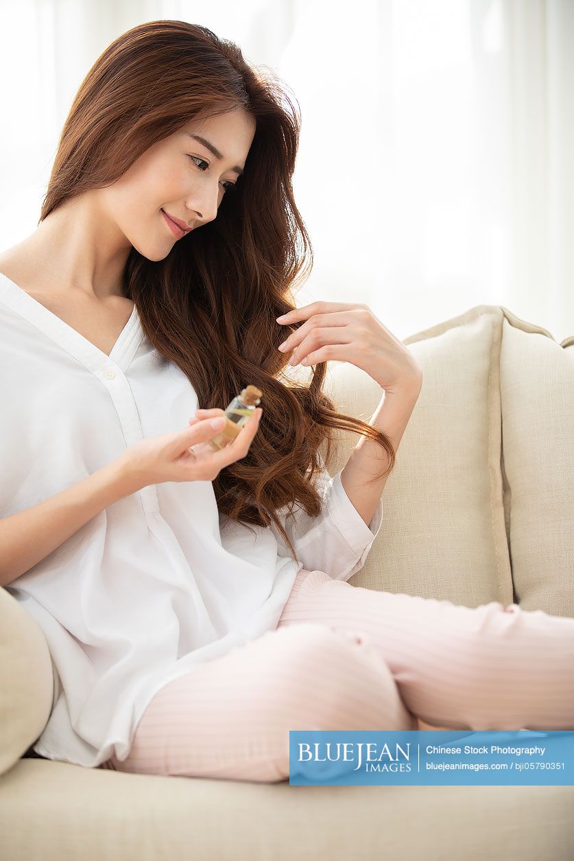 Young Chinese woman applying essential oil on hair