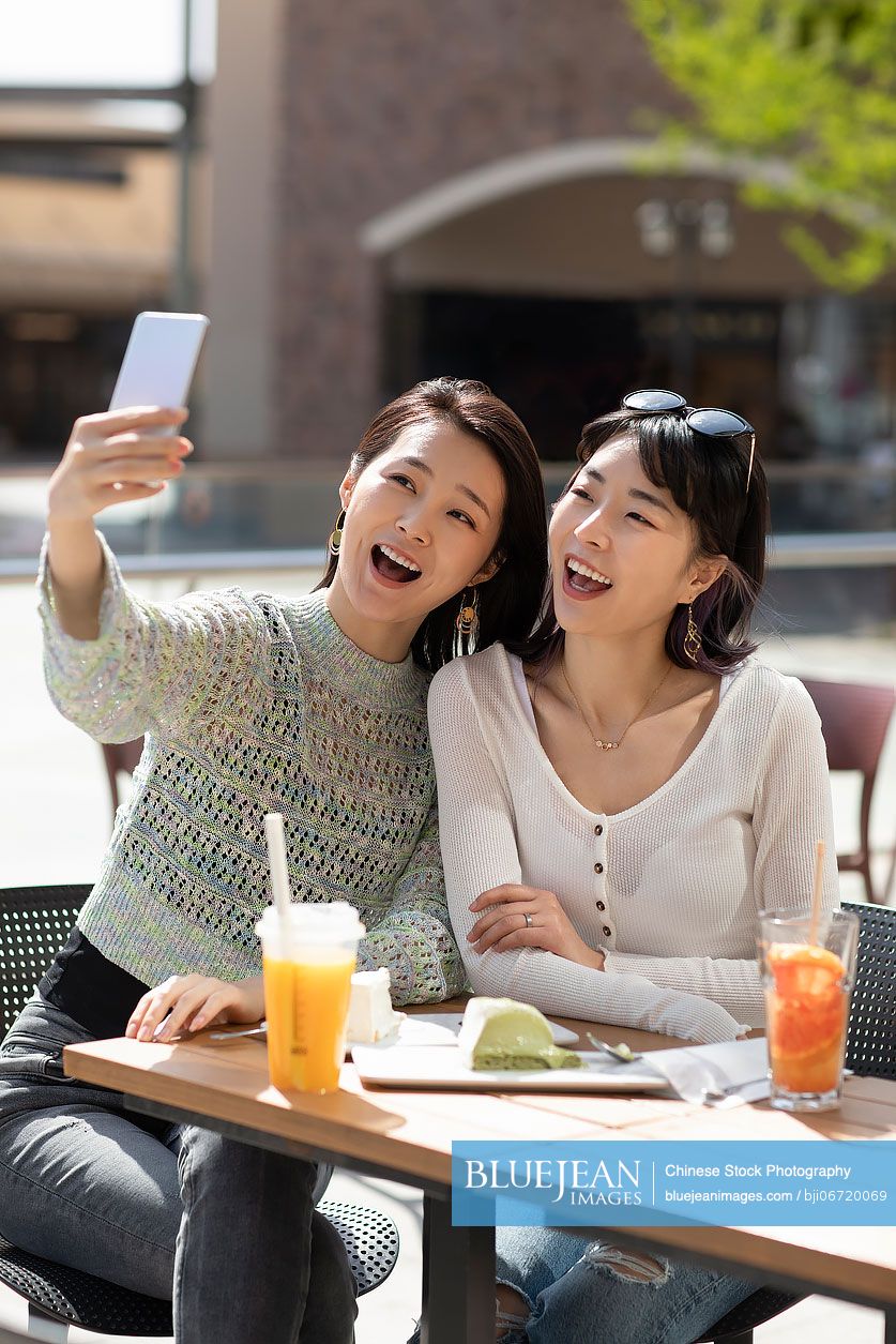 Happy best female friends taking selfie with smart phone