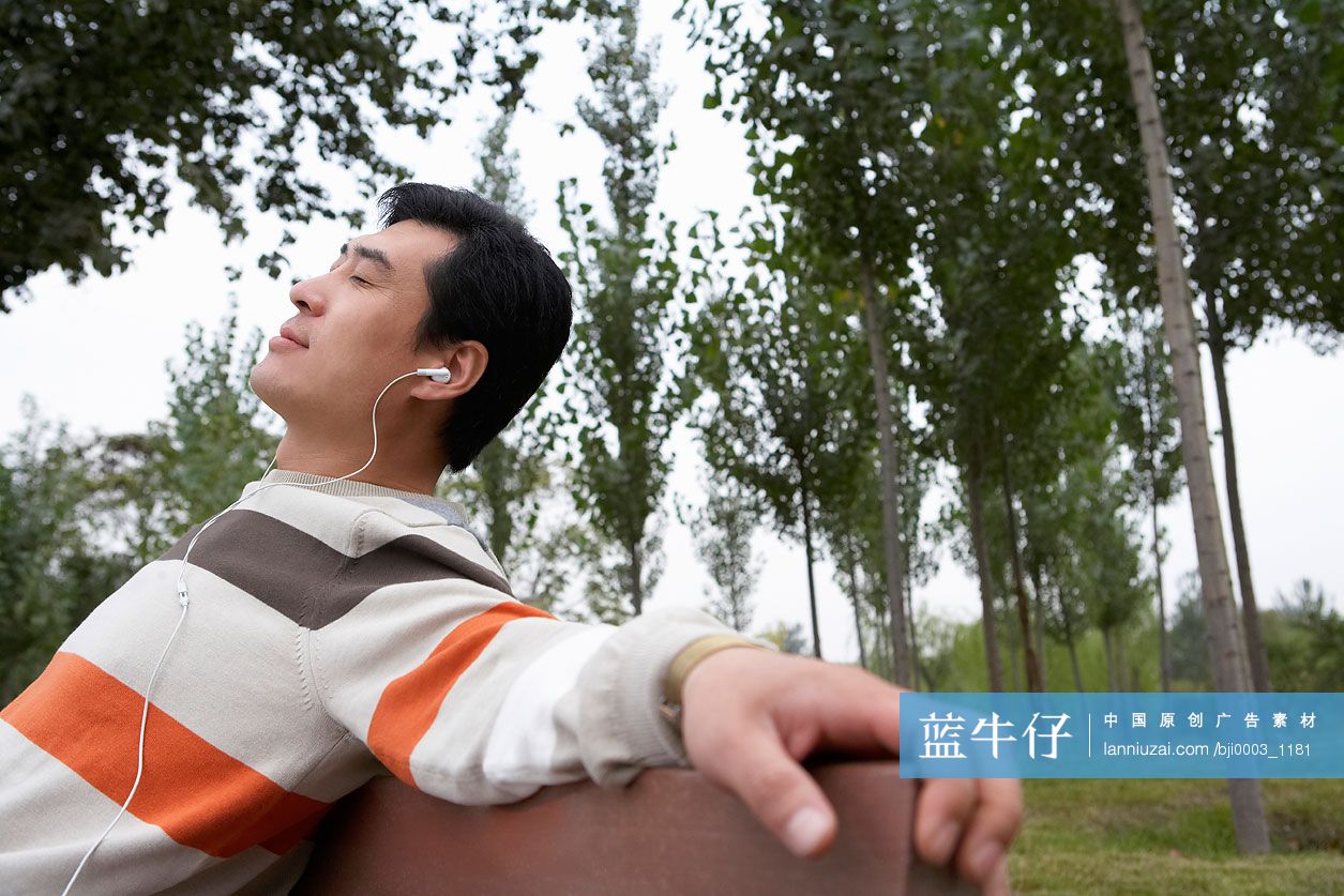 年轻男子在公园躺椅上听音乐