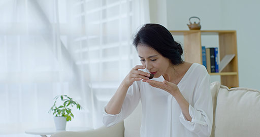 Happy mature Chinese woman drinking tea in living room,4K