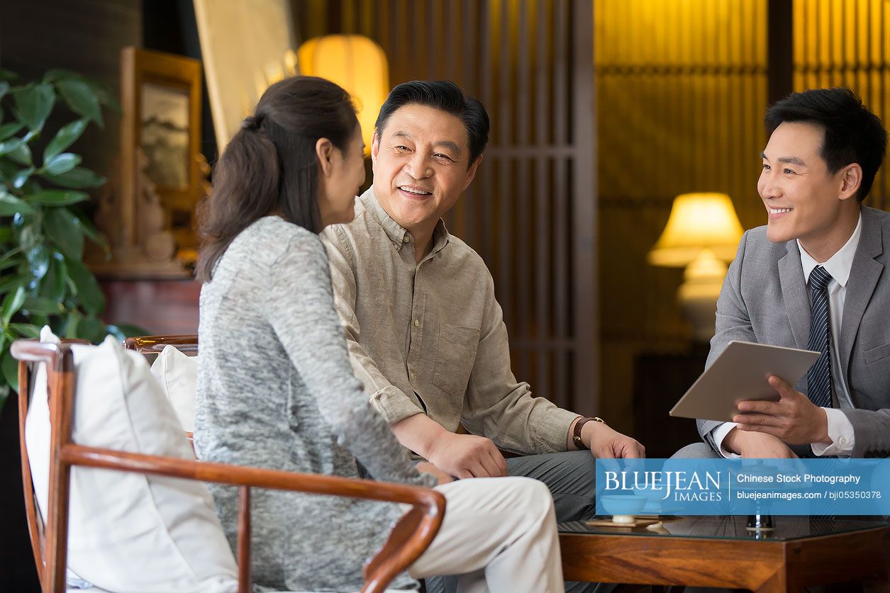 Confident Chinese financial consultant talking with mature couple