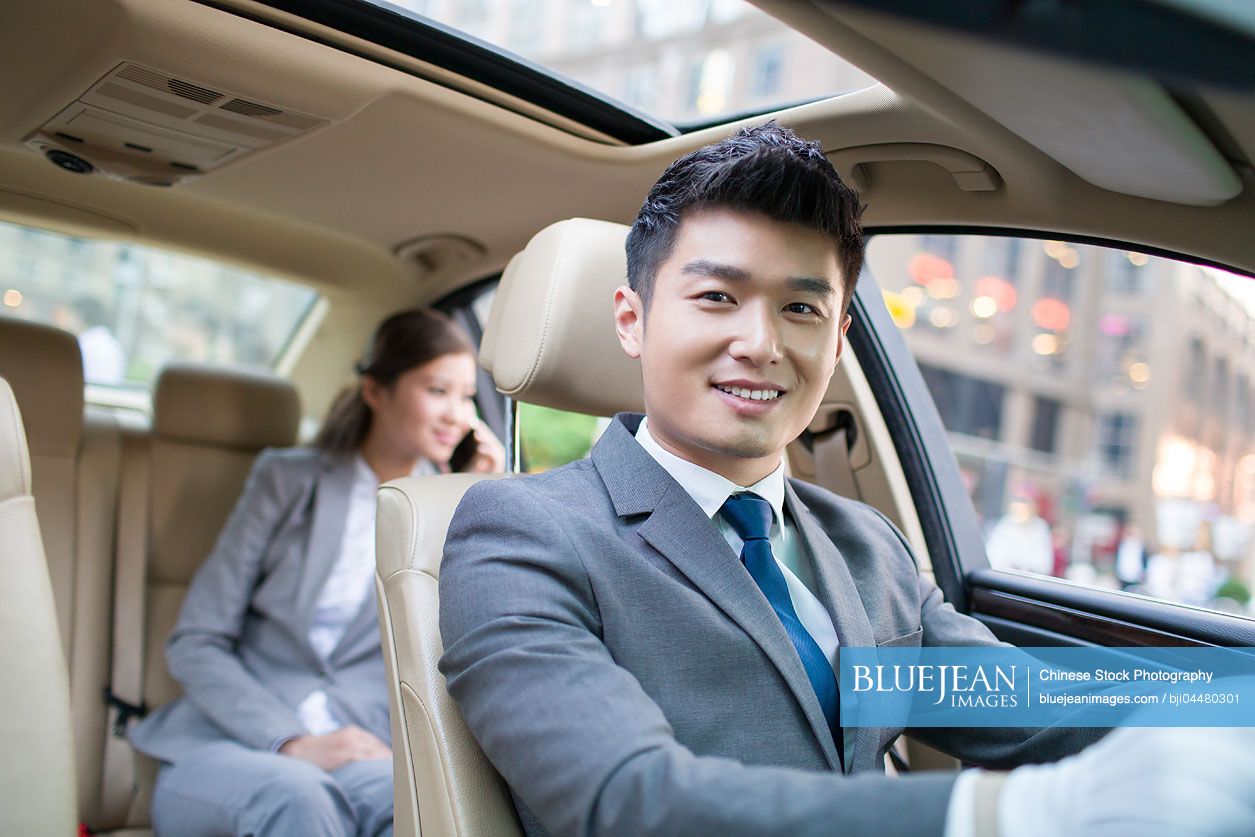Chinese chauffeur driving car for a Chinese businesswoman