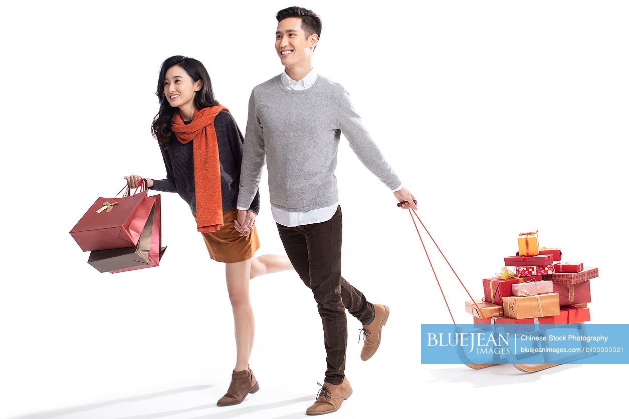 Happy young Chinese couple pulling sled