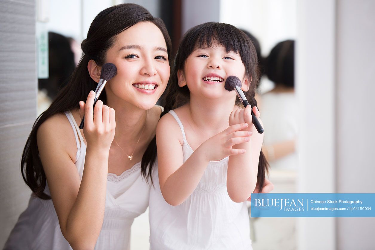 Chinese mother and daughter putting on makeup