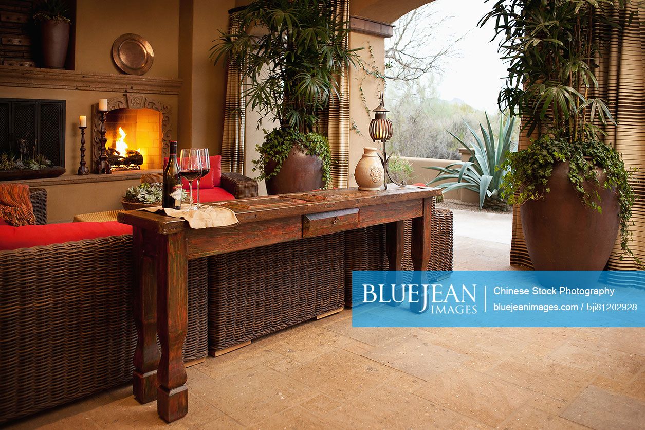 End table against wicker furniture and lit fireplace in living room at home; Scottsdale; USA