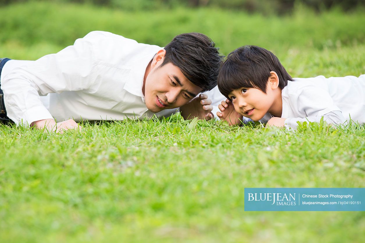 Chinese father and son lying on front listening