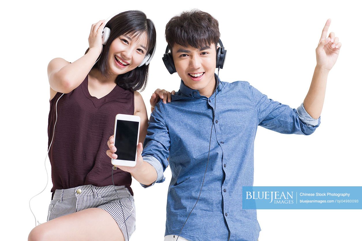 Happy young Chinese couple listening to music with smart phone