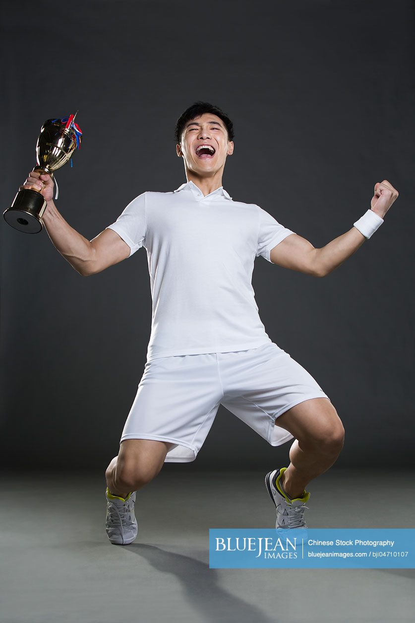 Young Chinese man cheering with a trophy