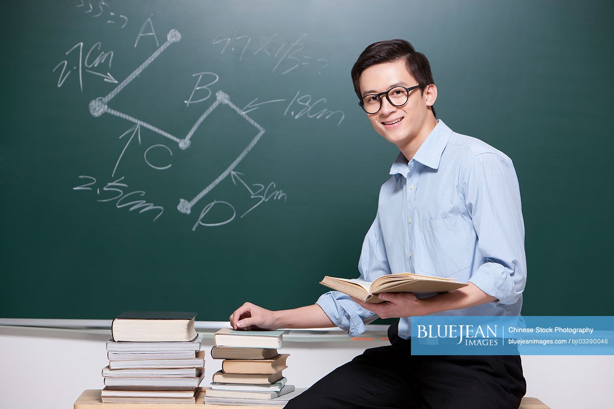 Confident Male Chinese teacher giving lessons in classroom
