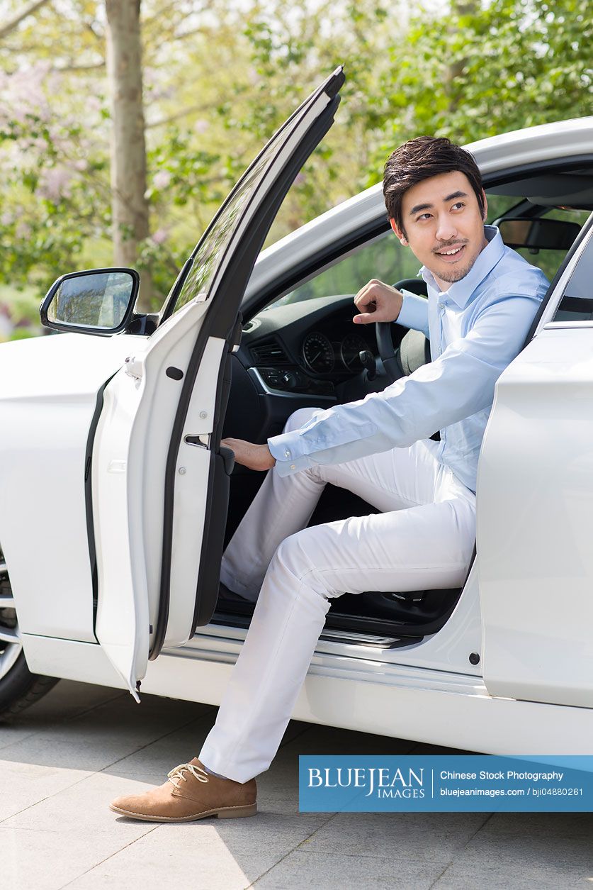 Young Chinese man opening car door