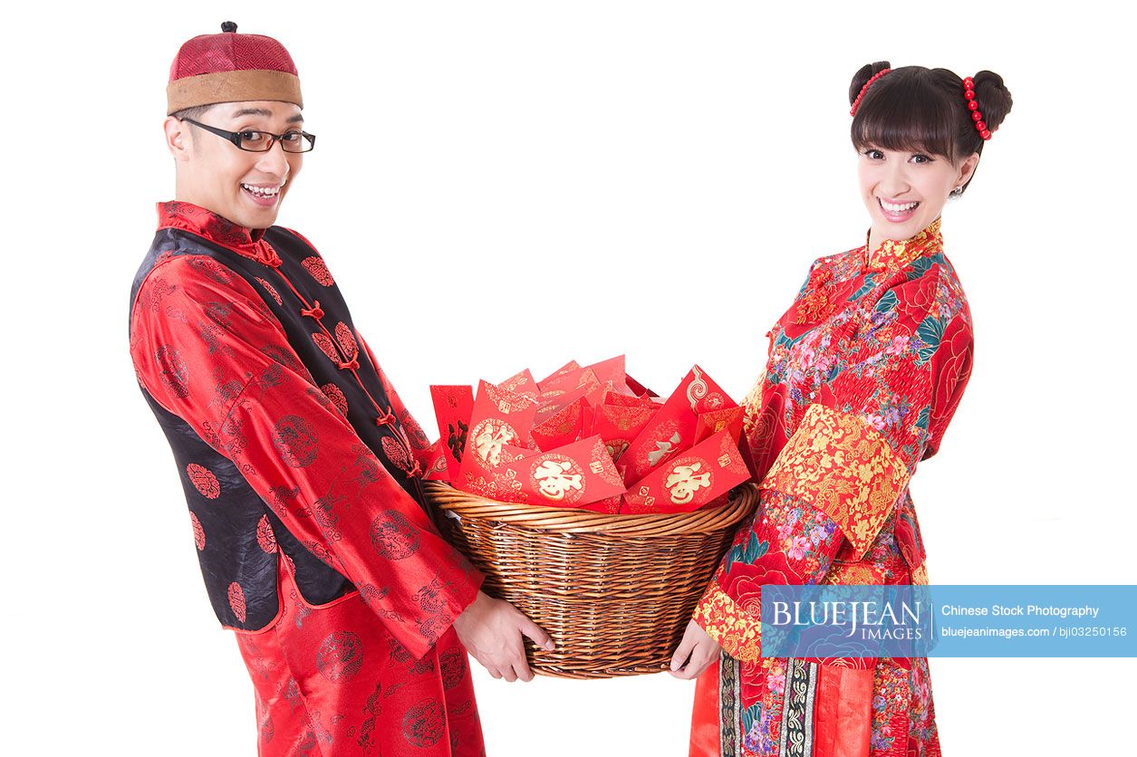 Cheerful young Chinese couple in Tang suit holding a basket of red pockets