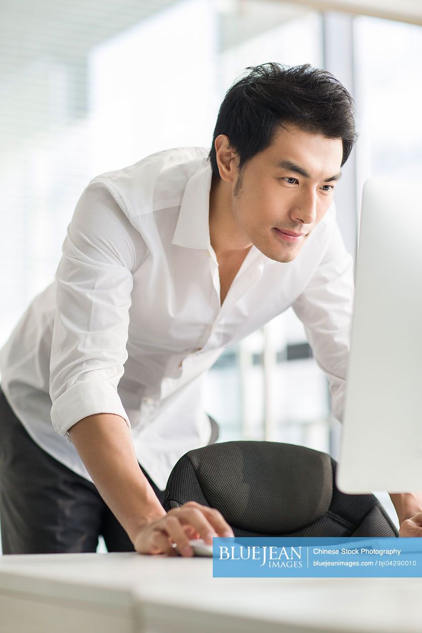 Young Chinese businessman using computer in office