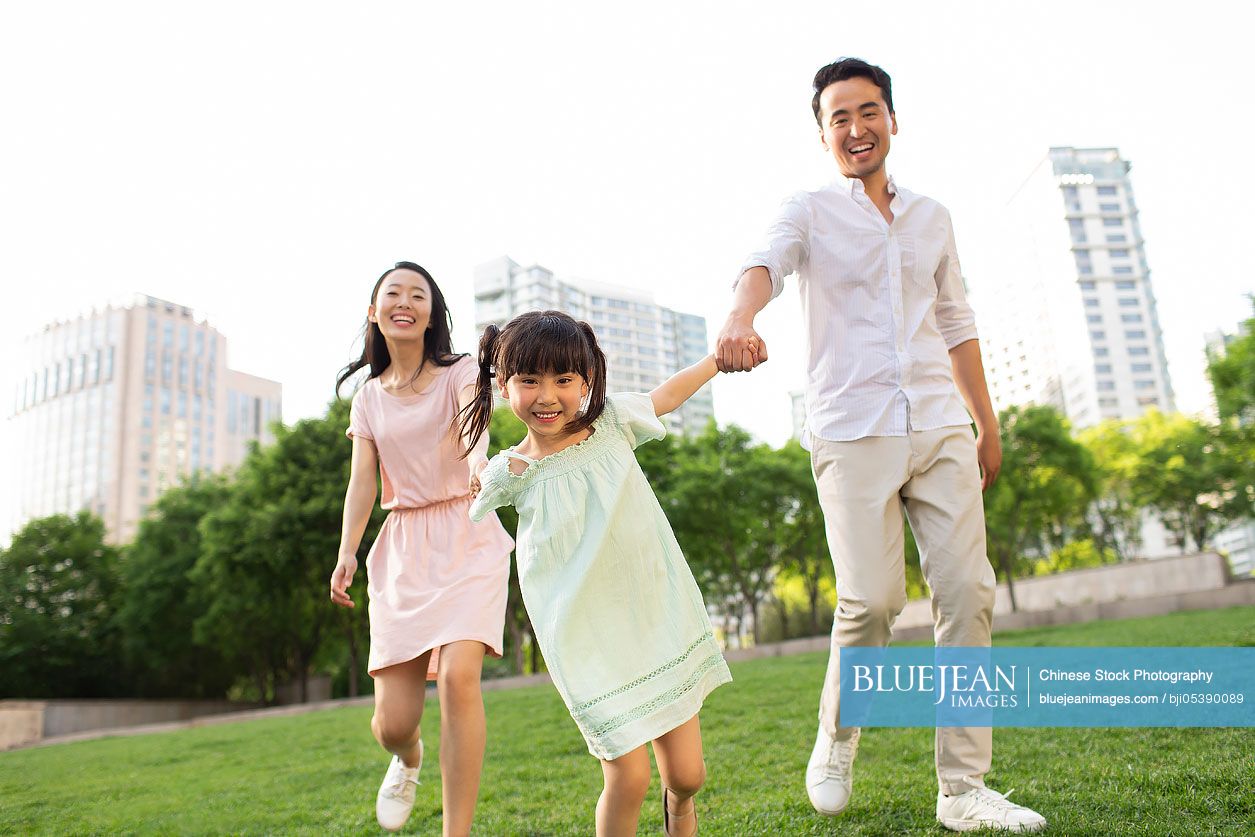 Happy young Chinese family playing in park