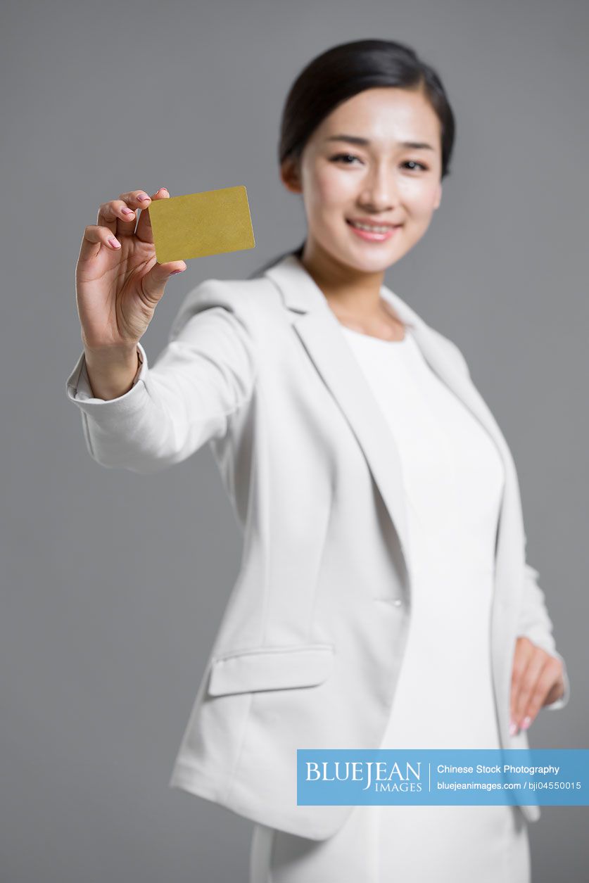 Happy young Chinese businesswoman holding a credit card