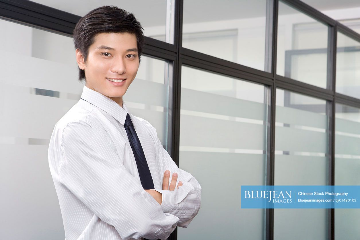 Young Chinese businessman standing in office