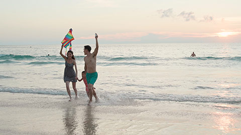 快乐的年轻家庭在沙滩放风筝