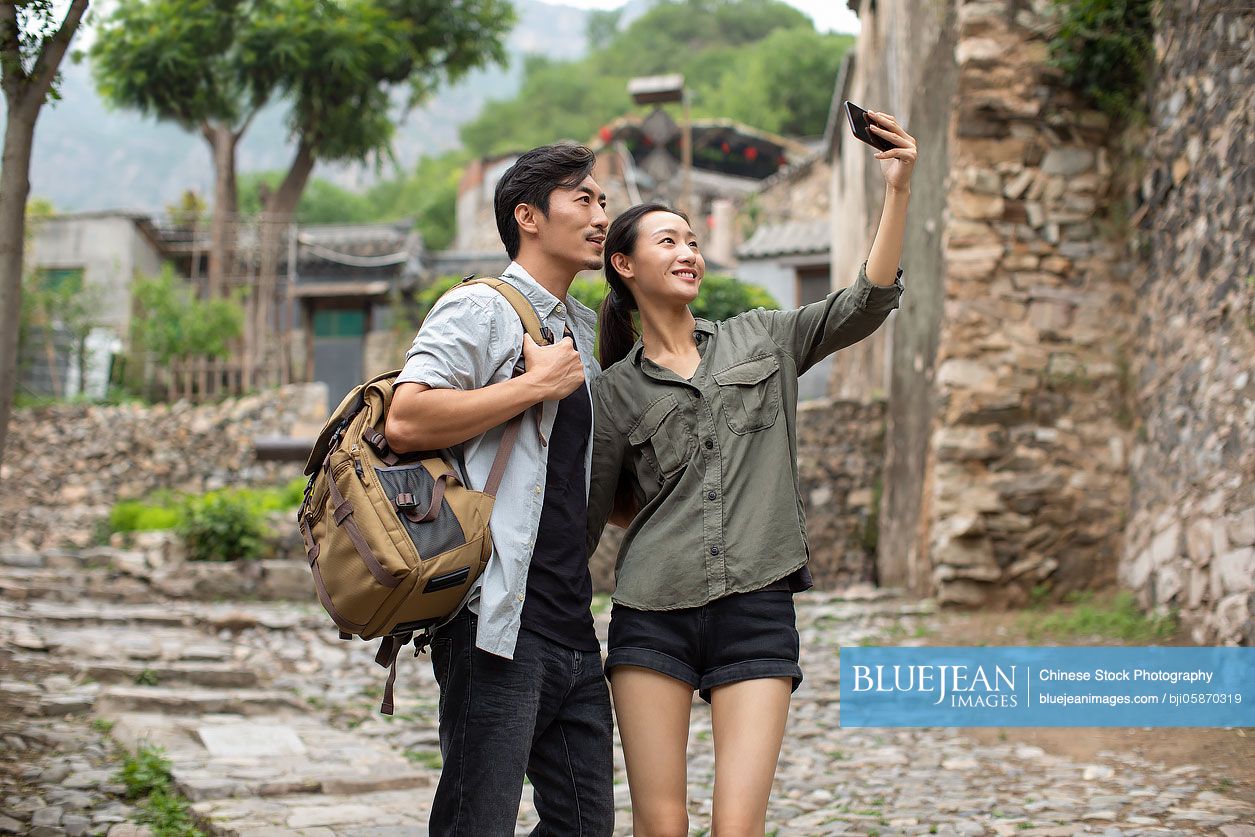 Young Chinese couple taking selfie with smartphone in village