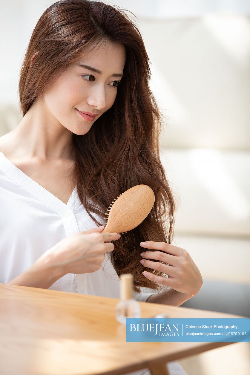Young Chinese woman brushing hair at home