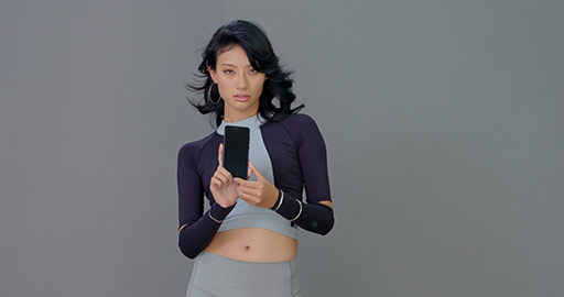 Futuristic young Chinese woman showing smartphone,4K