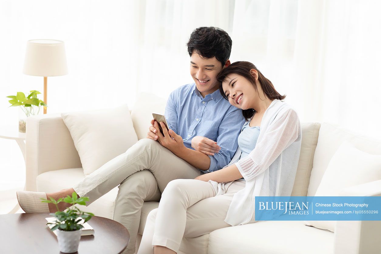 Cheerful young couple using smart phone